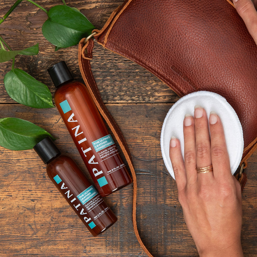 Top down views of leather care bottles with hand cleaning leather bag