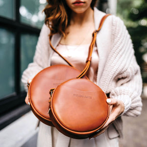 Person holding two Circle Crossbody Bags with a blurred background