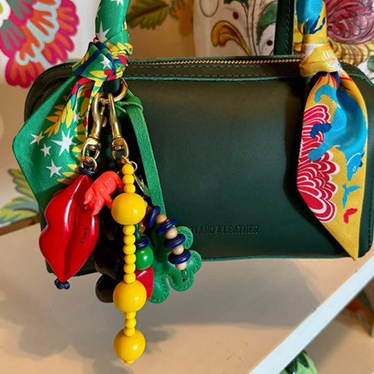 A dark green leather pouch or small bag with colorful decorative accessories