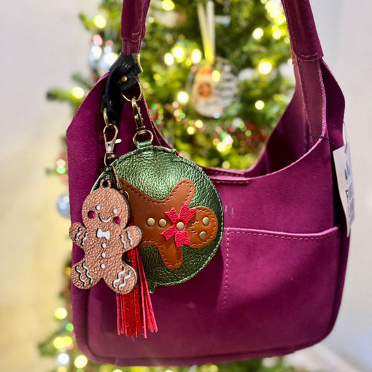 Pink handbag with decorative keychain in front of a Christmas tree