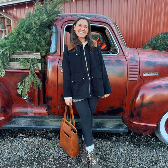 Woman standing in front of a vintage red truck with Christmas decorations.