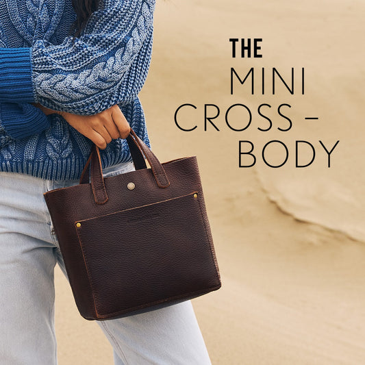 A model in a blue chunky sweater holding a Coldbrew Mini Crossbody Bag