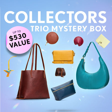 Promotional graphic for a 'Collectors Trio Mystery Box' featuring a collection of bags, wallets, and small goods. Set against a sparkly background with a pink badge indicating up to $530 value.