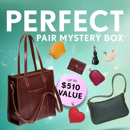 Promotional graphic for a 'Perfect Pair Mystery Box' featuring a collection of bags, wallets, and small goods. Set against a sparkly background with a pink badge indicating up to $510 value.