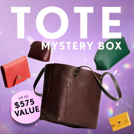 Promotional graphic for a 'Tote Mystery Box' featuring a collection of totes, wallets, and small goods. Set against a purple sparkly background with a pink badge indicating up to $575 value.