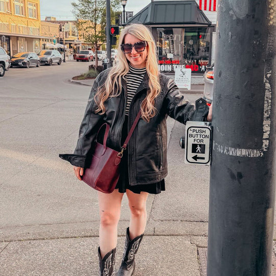 person standing at crosswalk wearing a PLG bag