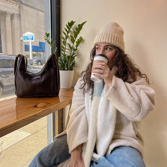 person drinking coffee with a PLG bag on the counter