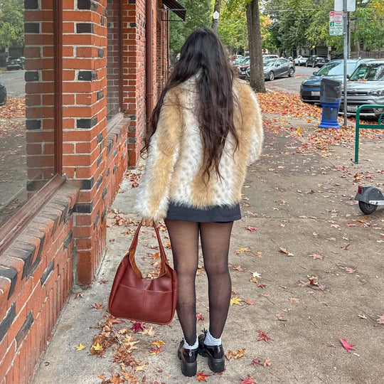 person standing in a fur coat holding a PLG Bag