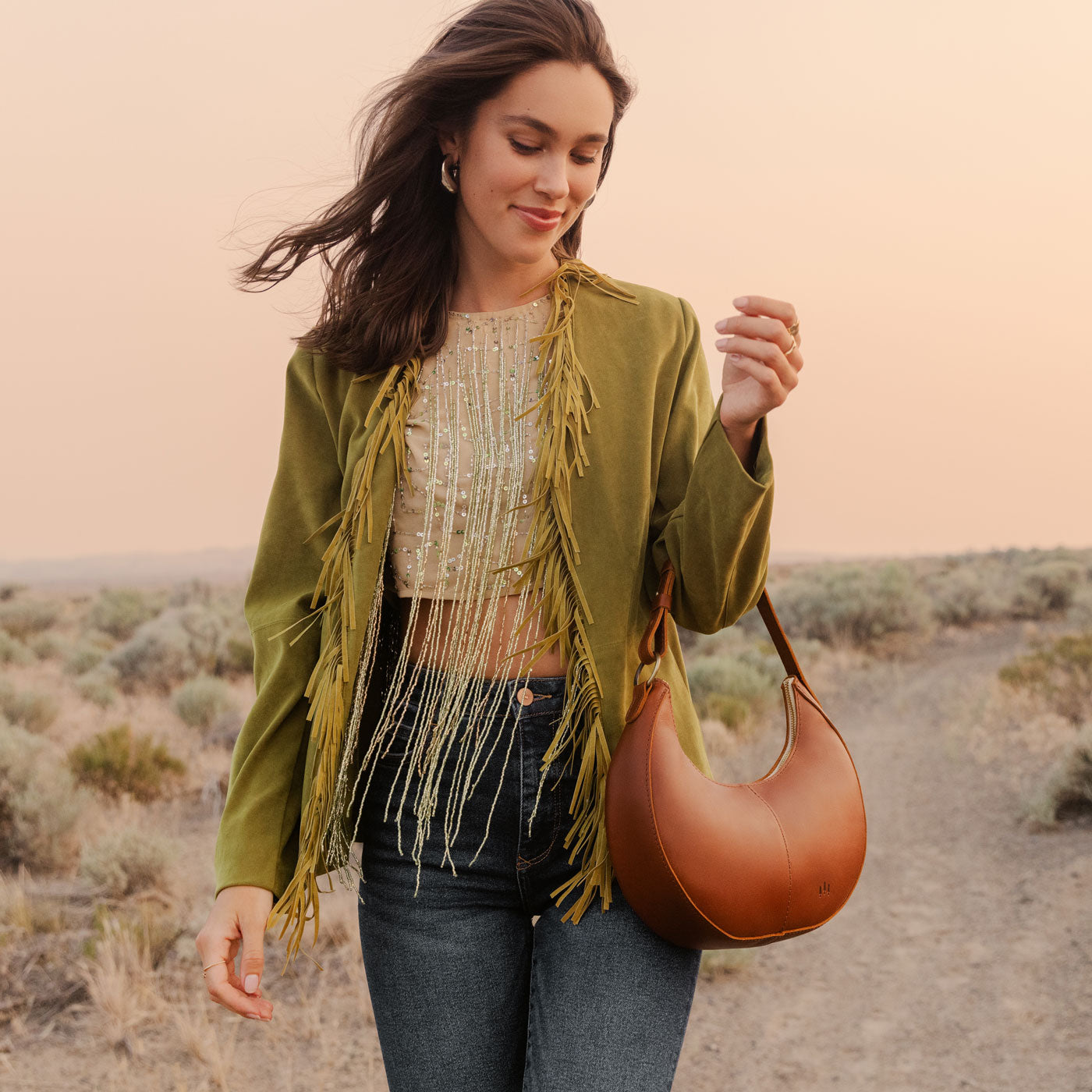 Honey*Classic | Model holding crescent shaped shoulder bag with zipper closure and adjustable strap