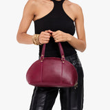 Orchid Small | Model holding a half circle crossbody bag with handles and removable crossbody strap 