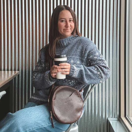 Woman holding coffee cup and wearing leather crossbody bag
