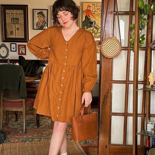 Woman in a brown dress holding a Mini Crossbody in a room with vintage decor.