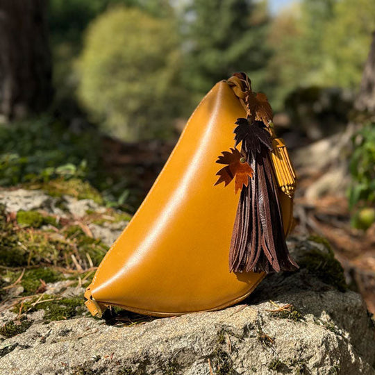 Mango Koala Sling Bag with tassels on a stone surface in a natural setting