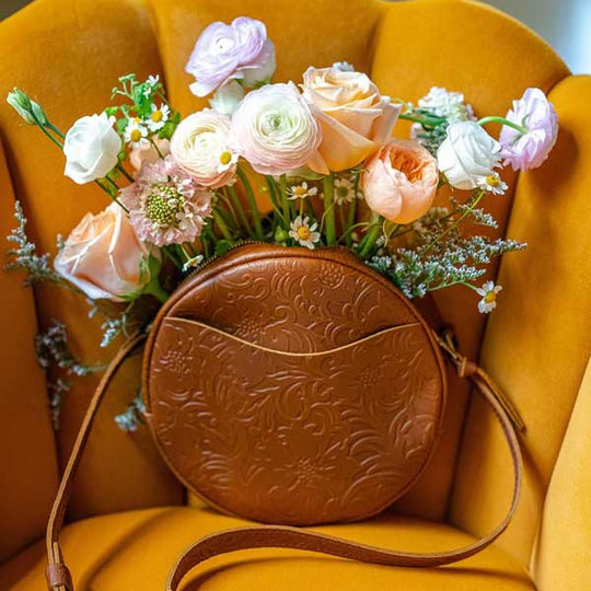 Brown embossed handbag with flowers on a yellow chair