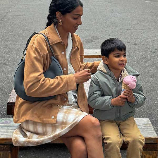 Woman and child sitting on a bench with the child holding an ice cream cone.