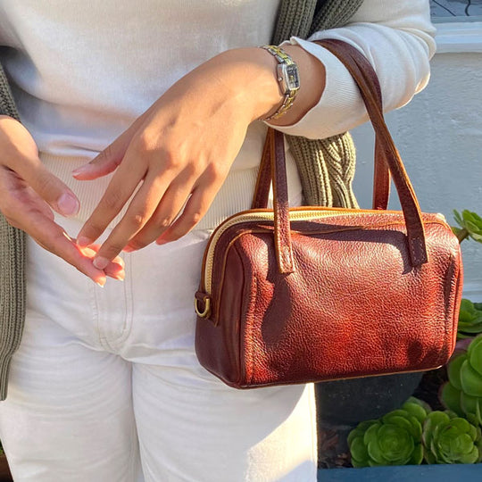 Nutmeg Sloan Doctor Bag held by a person wearing a white sweater and jeans, with a blurred background.