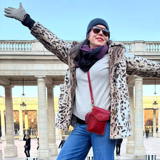 Person wearing a leopard print coat and sunglasses, standing in front of a architectural structure wearing a Chili Red Parker Phone Bag