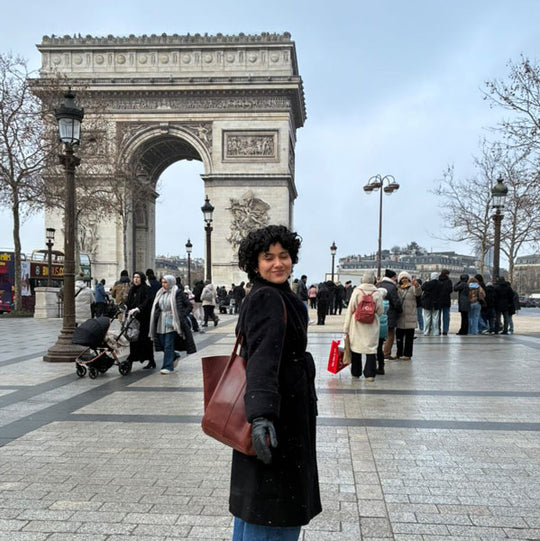 Person standing in front of the Arc de Triomphe in Paris with a Nutmeg Devan Tote Bag