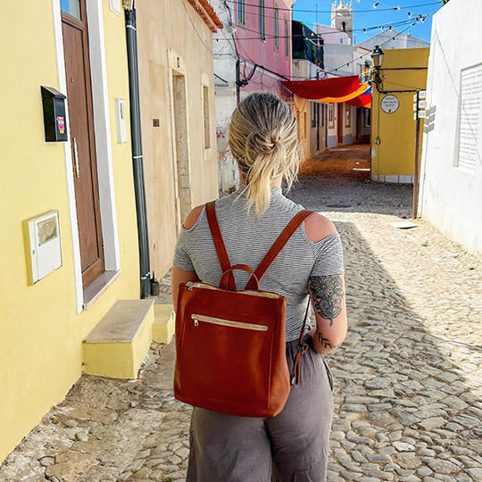 Back of women wearing a brown backpack in a colorful alley