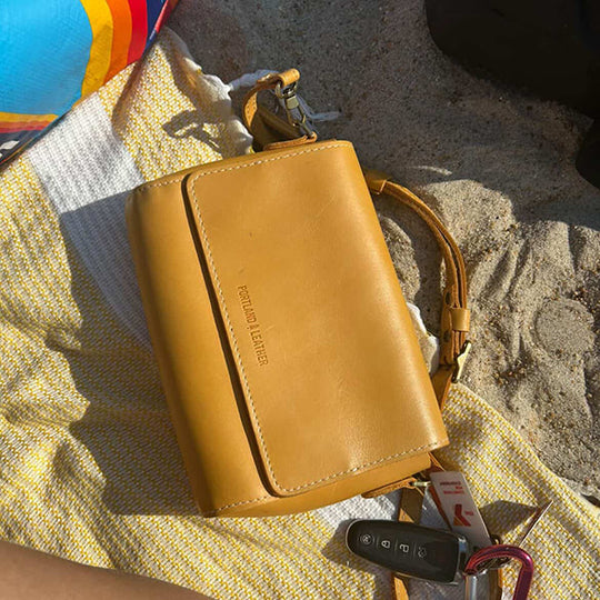 A yellow bag laying on a beach blanket