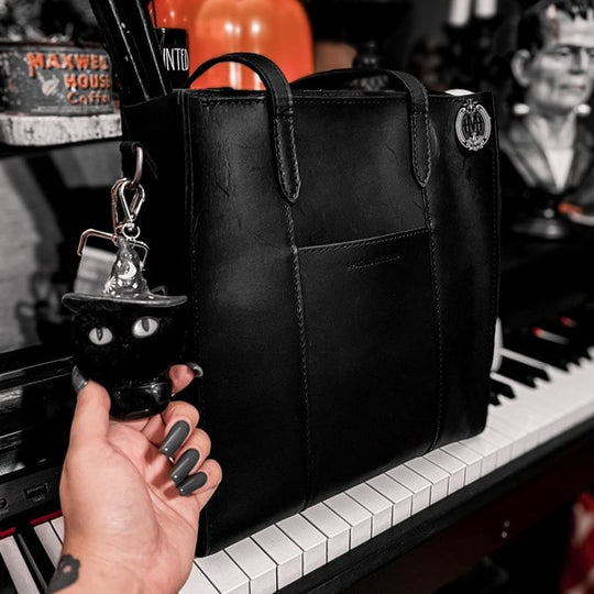A black Lola Crossbody Tote sitting on a piano