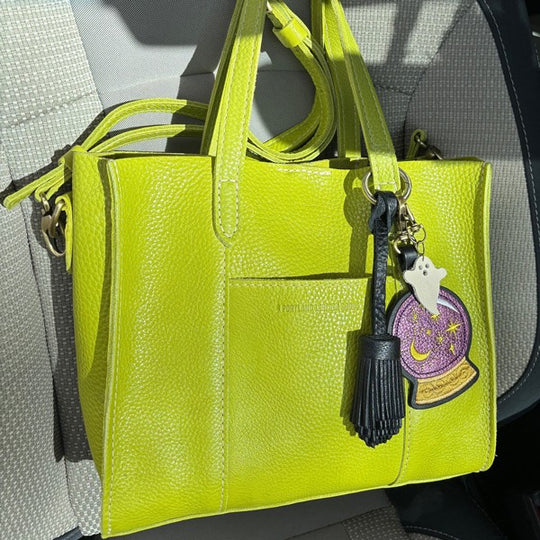 A lime green lola crossbody tote with a crystal ball keychain