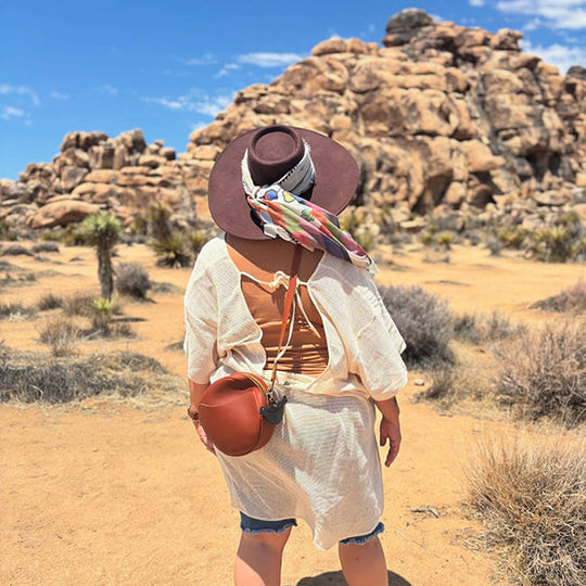 Back of women wearing a brown crossbody with a desert landscape