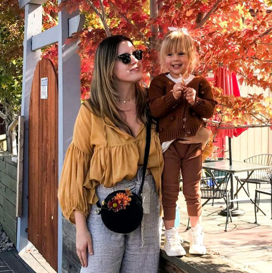 A parent holding on to their child and carrying a Black Circle Crossbody Bag