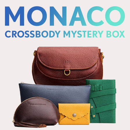 Monaco Crossbody in Madrone next to Mockingbird Pouch, Eclipse Makeup Bag, Fortune Cookie Keychain, Petunia Pouch, Sunglasses Case, and Lovebug Wallet. Text reads "Monaco Crossbody Mystery Box" 