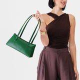 Bacalar | Woman holding a dark green leather bowler bag against a white background