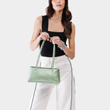 Beetle | Woman holding a shiny green leather bowler bag against a white background