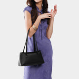 Black | Woman wearing a black leather bowler bag against a white background