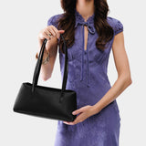 Black | Woman holding a black leather bowler bag against a white background