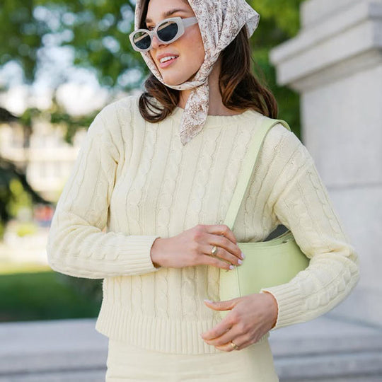 A person in sunglasses and headscarf holding a Lucy Shoulder Bag