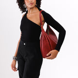 Chili Red Large | Model holding u-shaped, flat-bottomed leather shoulder bag with adjustable strap