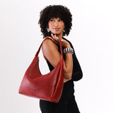 Chili Red Large | Model holding u-shaped, flat-bottomed leather shoulder bag with adjustable strap