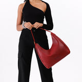 Chili Red Large | Model holding u-shaped, flat-bottomed leather shoulder bag with adjustable strap