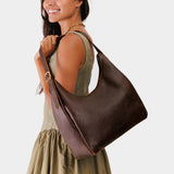 Coldbrew Large | Model holding u-shaped, flat-bottomed leather shoulder bag with adjustable strap
