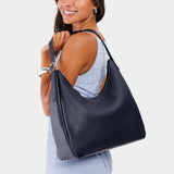 Night Owl Large | Model holding u-shaped, flat-bottomed leather shoulder bag with adjustable strap
