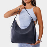 Night Owl Large | Model holding u-shaped, flat-bottomed leather shoulder bag with adjustable strap