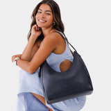 Night Owl Large | Model holding u-shaped, flat-bottomed leather shoulder bag with adjustable strap