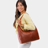 Nutmeg Large | Model holding u-shaped, flat-bottomed leather shoulder bag with adjustable strap