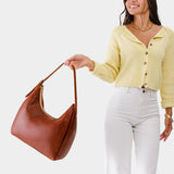 Nutmeg Large | Model holding u-shaped, flat-bottomed leather shoulder bag with adjustable strap