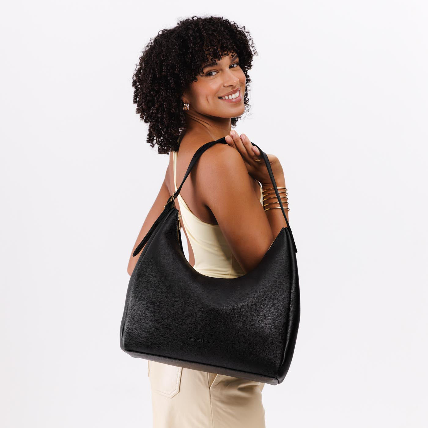 Pebbled--black*Large | Model holding u-shaped, flat-bottomed leather shoulder bag with adjustable strap