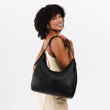 Pebbled--black Large | Model holding u-shaped, flat-bottomed leather shoulder bag with adjustable strap