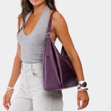Plum Large | Model holding u-shaped, flat-bottomed leather shoulder bag with adjustable strap