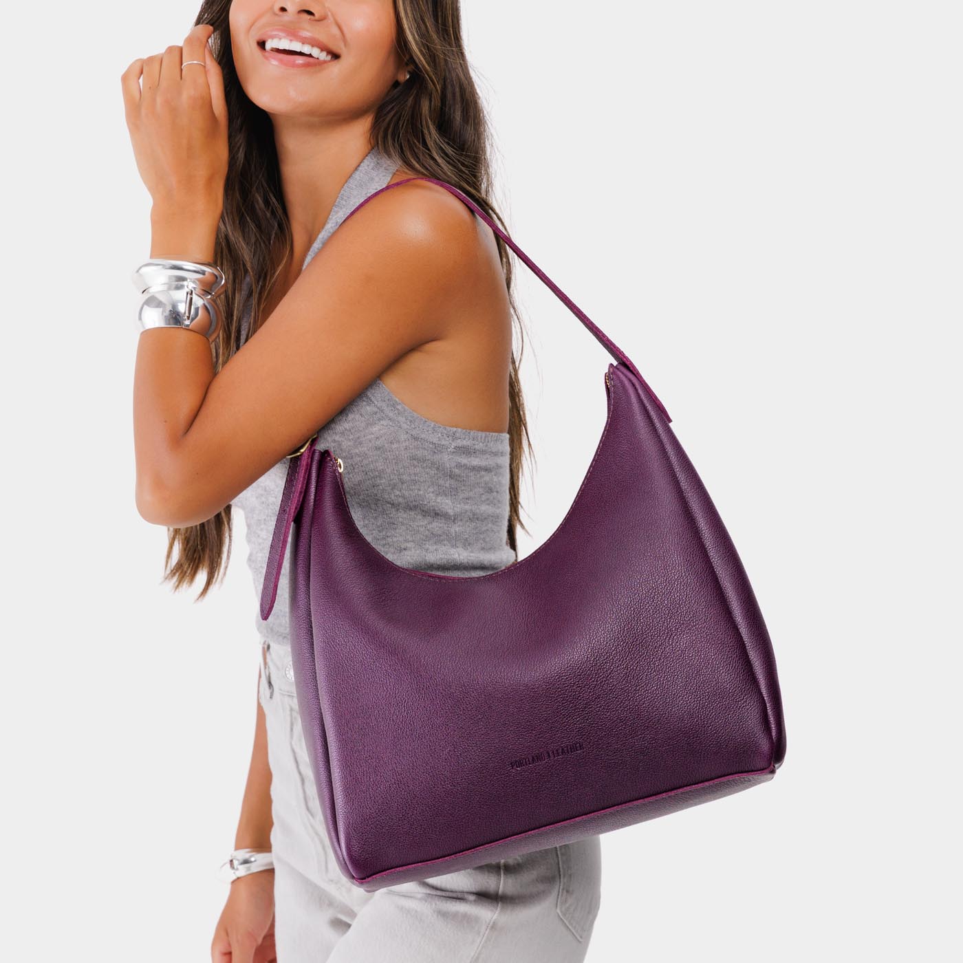 Plum*Large | Model holding u-shaped, flat-bottomed leather shoulder bag with adjustable strap