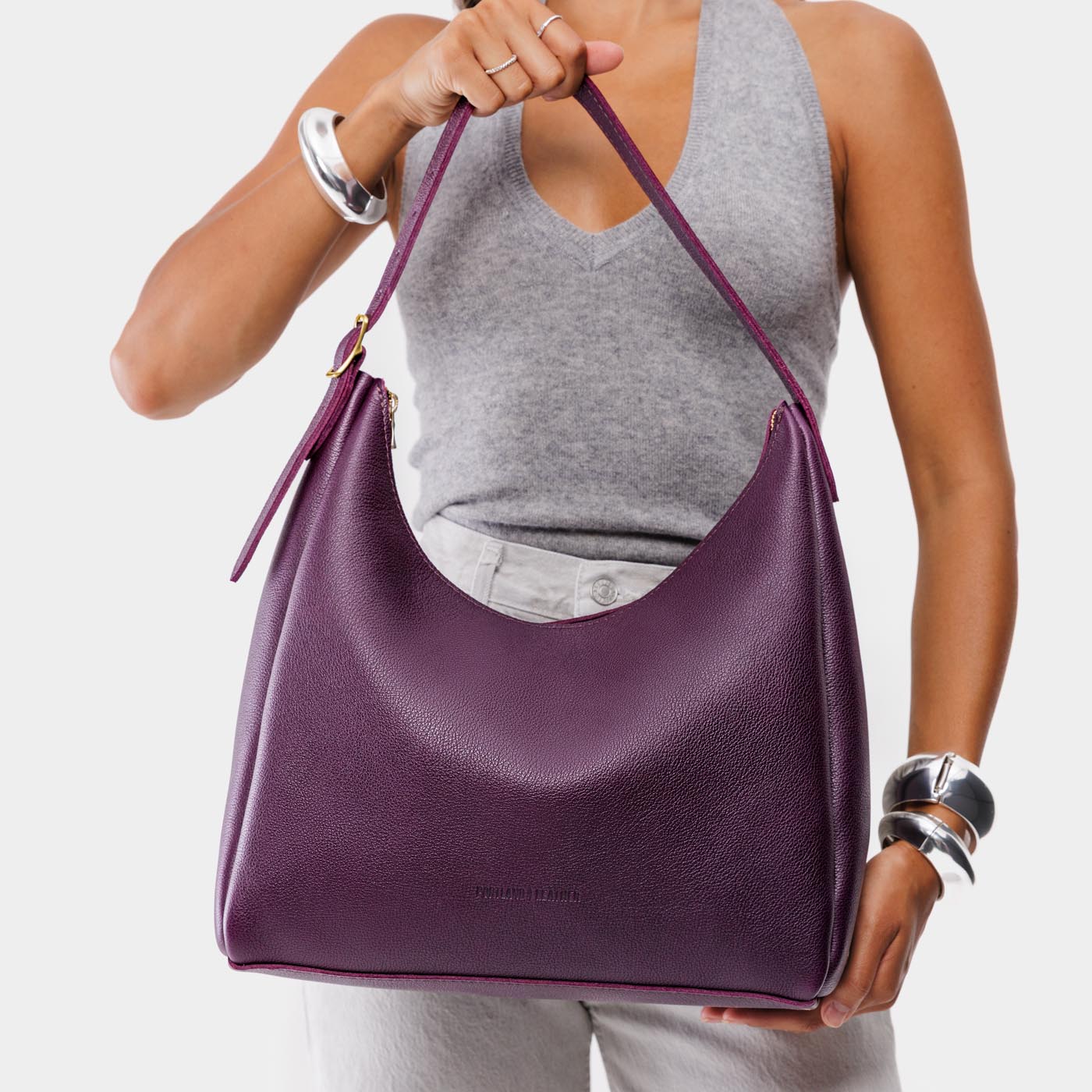 Plum*Large | Model holding u-shaped, flat-bottomed leather shoulder bag with adjustable strap