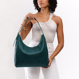 Sea Glass Large | Model holding u-shaped, flat-bottomed leather shoulder bag with adjustable strap