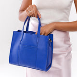 Astro Blue Classic | Model holding structured mid-size tote bag with overlapping panels and crossbody strap